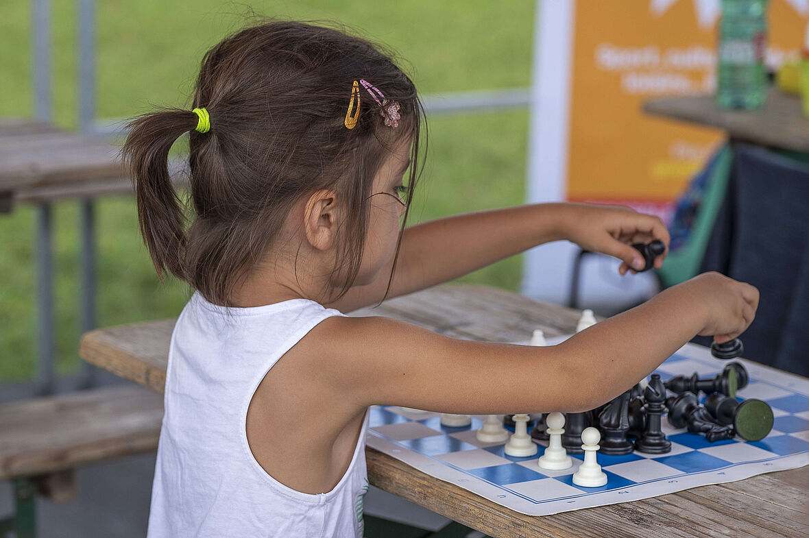 une enfant place les pions d'échec sur l'échiquier