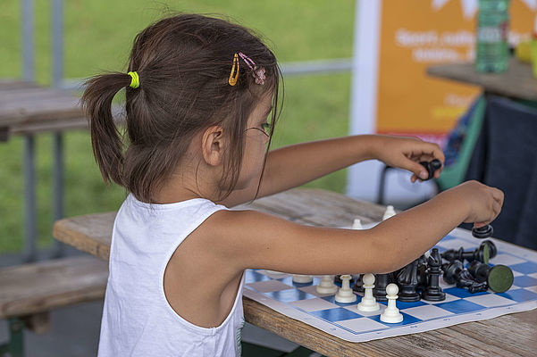 une enfant place les pions d'échec sur l'échiquier