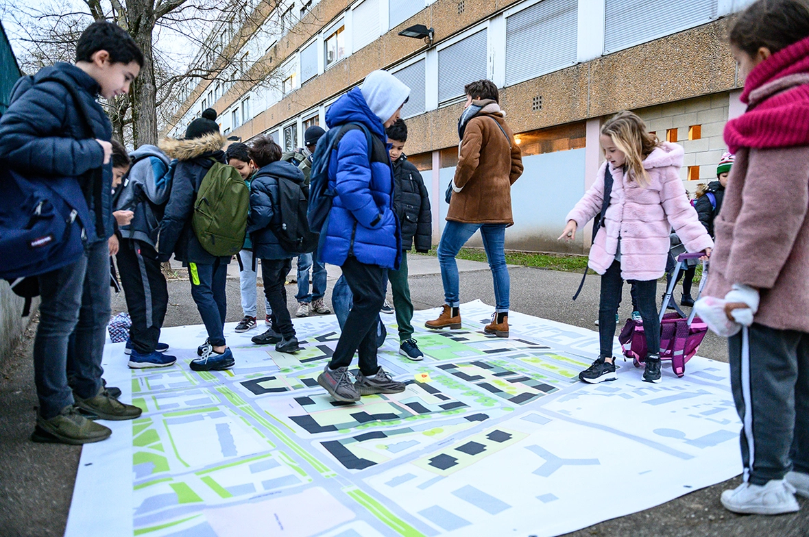 Une photo d'enfants en train de regarder un plan de transformation du quartier Mermoz Sud